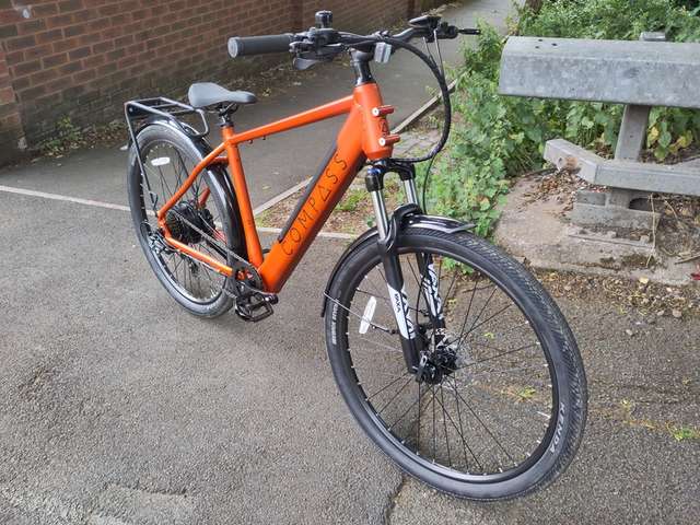 An orange Compass ebike, seen from front right